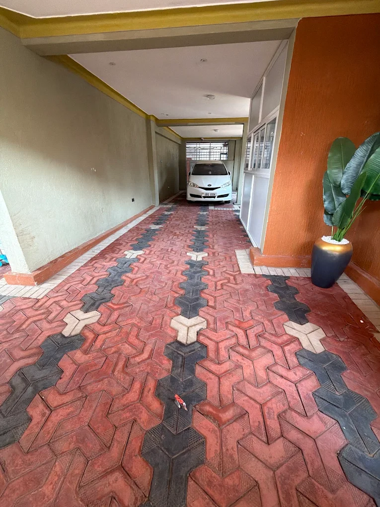 The paved, roofed driveway inside the Leon Villas compound with a car parked at the far end