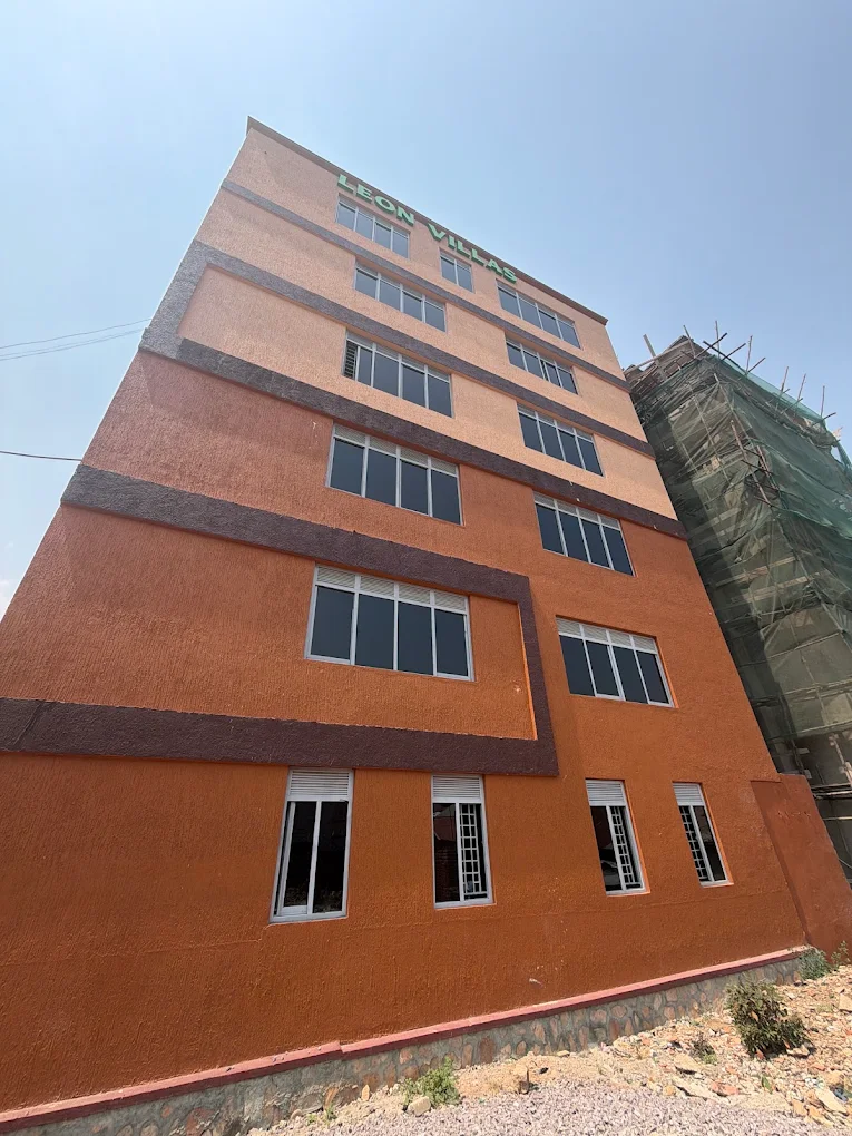 The side wall of Leon Villas in terracotta and brown, rising above the road